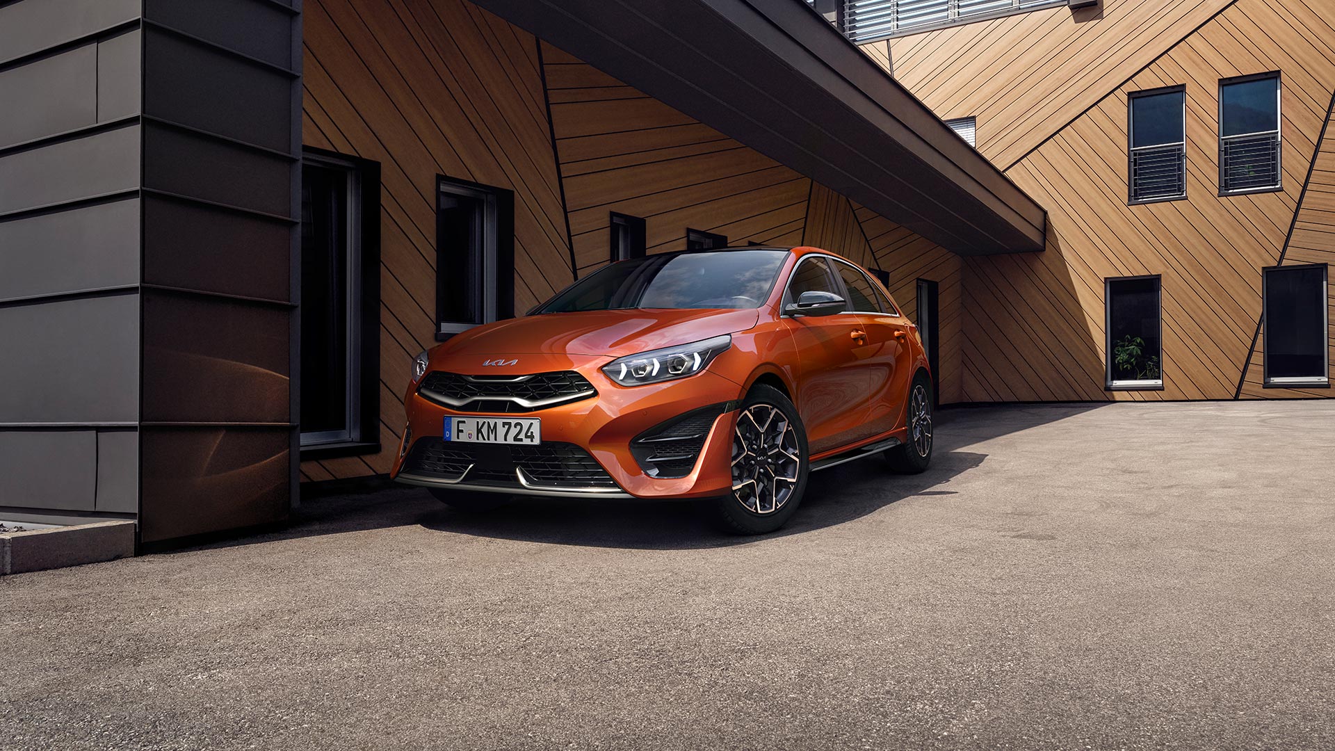 Orangener Kia Ceed GT-Line vor einem Gebäude zur Modellpräsentation